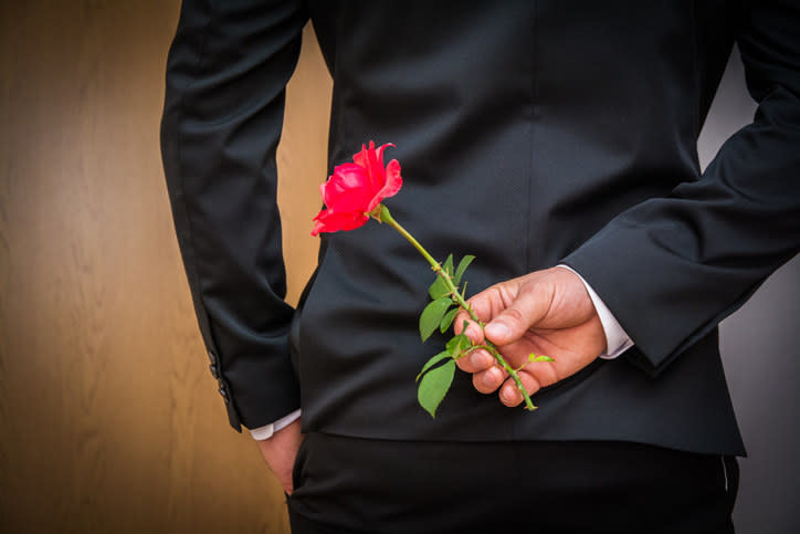 Someone holding a rose behind their back for a date