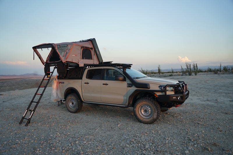 A Ford ranger parked with its rooftop tent opened.