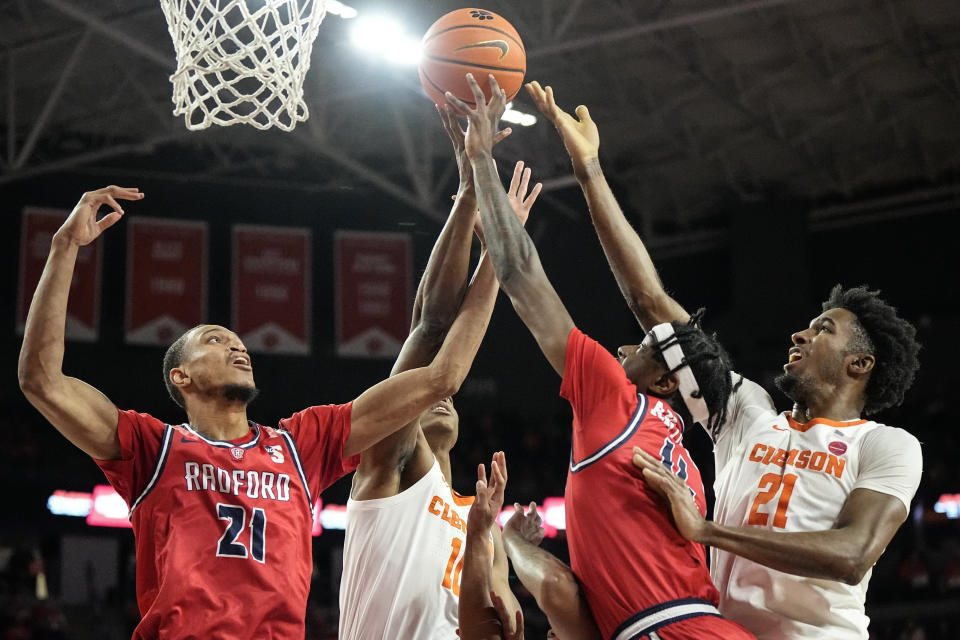Clemson forward Chauncey Wiggins (21) and Radford center D'Auntray Pierce (21) vie for a rebound during the first half of an NCAA college basketball game, Friday, Dec. 29, 2023, in Clemson. (AP Photo/Mike Stewart)