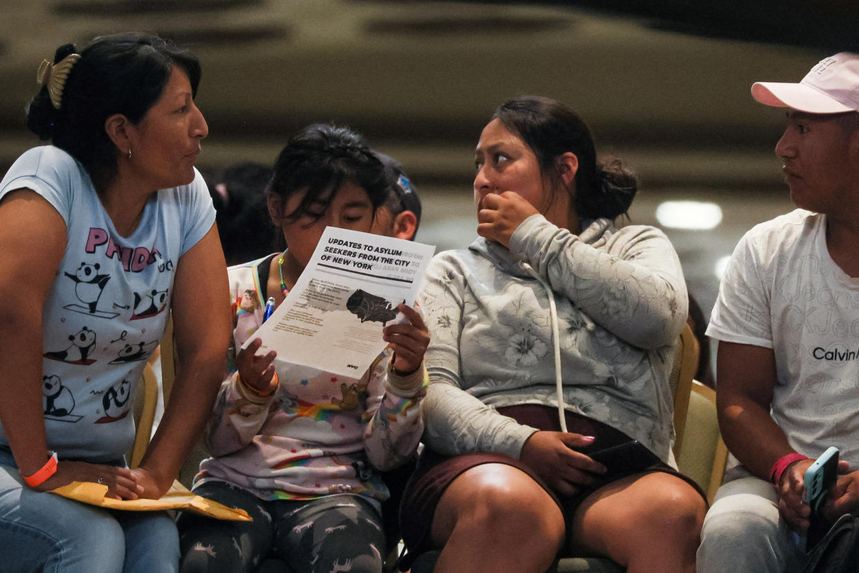 Several asylum seekers sit inside the Roosevelt Hotel, where migrants are being processed and housed.