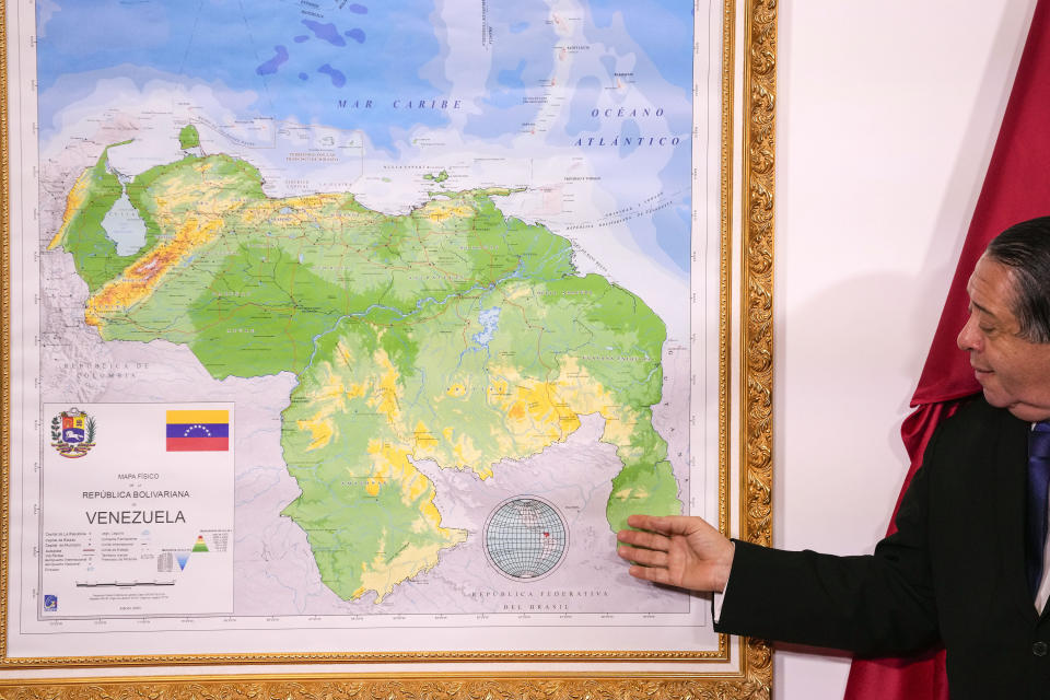 Chairman of the Special Commission for the Defense of Guyana Essequibo Hermann Escarra, stands next to Venezuela's new map that includes the Essequibo territory, a swath of land that is administered and controlled by Guyana but claimed by Venezuela, during an unveiling ceremony in Caracas, Venezuela, Friday, Dec. 8, 2023. (AP Photo/Matias Delacroix)