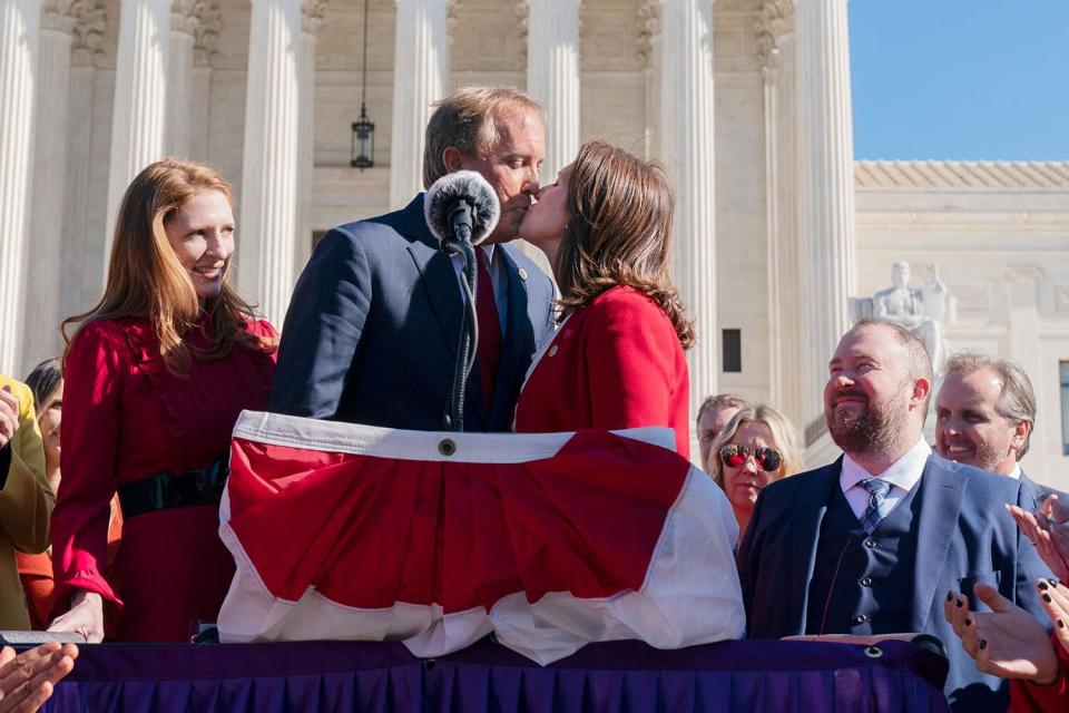 Texas Attorney General Ken Paxton, center, kisses his wife and Texas State Sen. Angela Paxton, on the occasion of their wedding anniversary, as they speak to anti-abortion activists at a rally outside the Supreme Court, after hearing arguments on abortion, at the court on Capitol Hill in Washington Abortion Supreme Court, Washington, United States - 01 Nov 2021