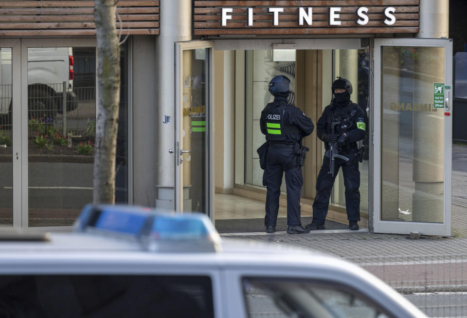 Armed police officers stay in front of a health club in Duisburg, Germany, Tuesday, April 18, 2023. German police say several people have been injured in an attack at a gym in the western city of Duisburg. Tuesday evening’s attack occurred in the old city of Duisburg and police asked residents to avoid the area. (Christoph Reichwein/dpa via AP)