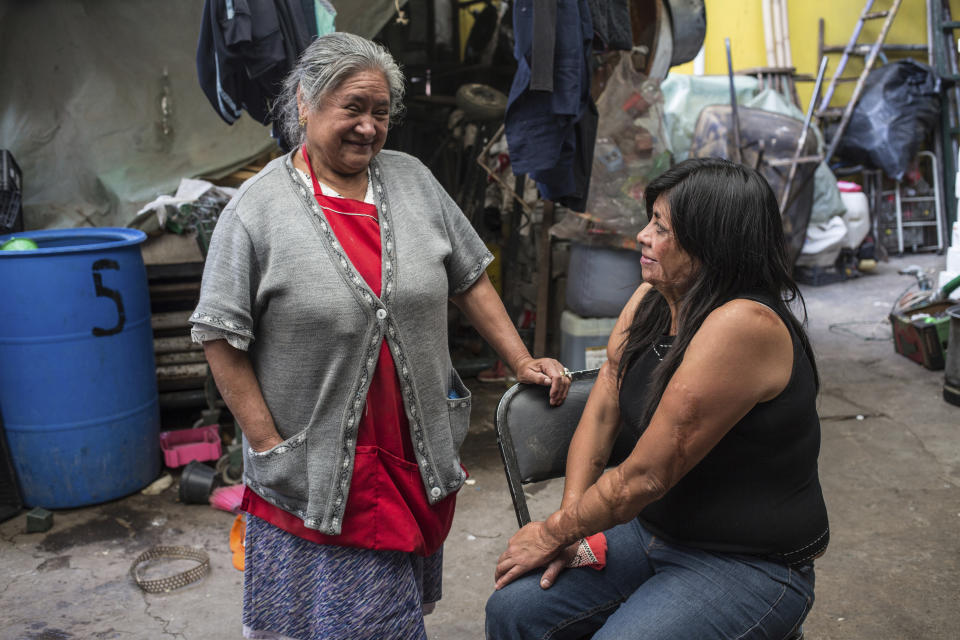 Elisa Xolalpa, quien sobrevivió a un ataque con ácido por su expareja hace 20 años cuando ella tenía 18 años, habla con su mamá Carmen Martínez en el patio de la casa de sus padres en Ciudad de México, el sábado 12 de junio de 2021. (AP Foto/Ginnette Riquelme)