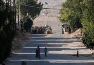 People walk near a checkpoint for Asayish security force in Aleppo's Sheikh Maqsoud neighbourhood, Syria July 15, 2017. REUTERS/Omar Sanadiki