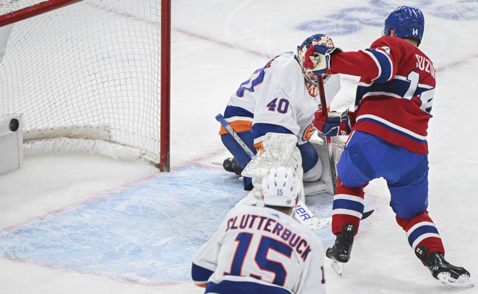 Montreal Canadiens' Nick Suzuki (14) scores against New York Islanders goaltender Semyon Varlamov as Islanders' Cal Clutterbuck (15) watches during the first period of an NHL hockey game Thursday, Jan. 25, 2024, in Montreal. (Graham Hughes/The Canadian Press via AP)