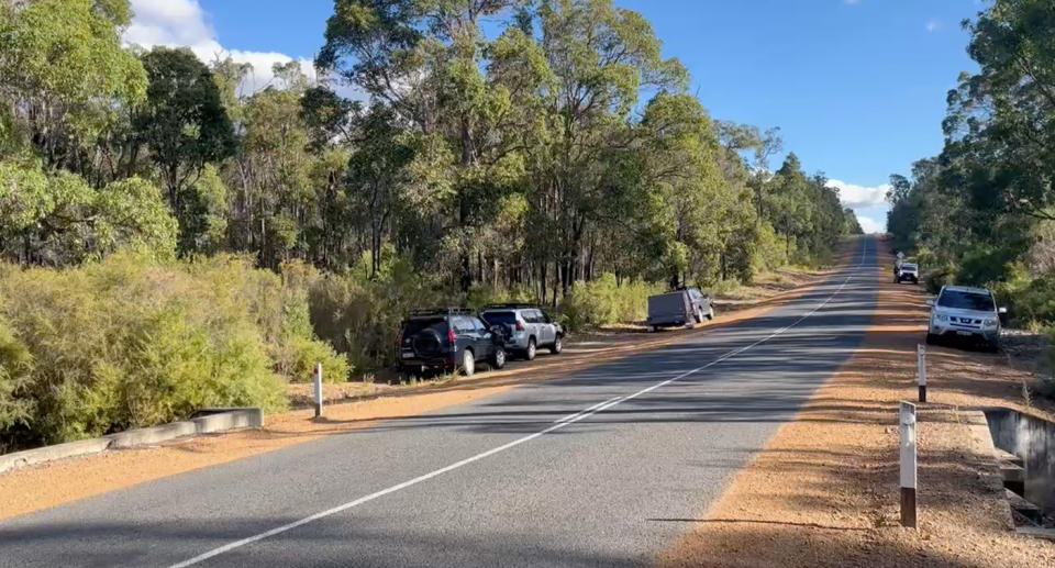 A highway can be seen in thick bushland, with several vehicles dotted at either side of the road as police responded to the discovery of human remains. 