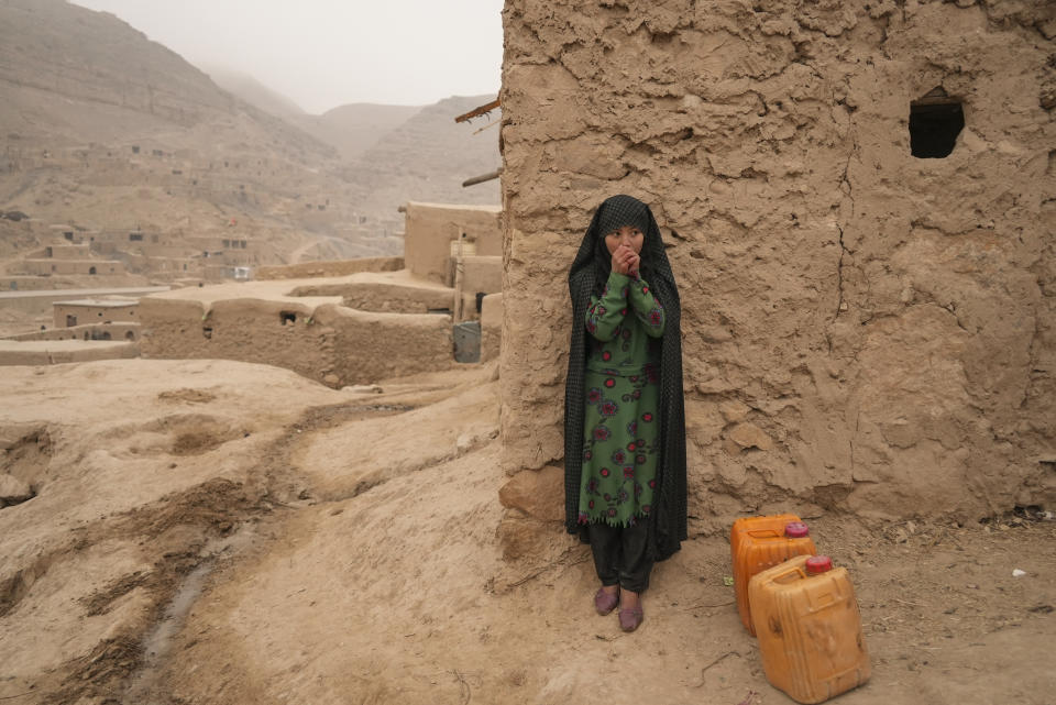 FILE - An Afghan girl warms up her hands as she is resting from carrying the water in Balucha, Afghanistan, Monday, Dec. 14, 2021. The Middle East is one of the most vulnerable regions in the world to the impact of climate change, and already the effects are being seen. This year's annual U.N. climate change conference, known as COP27, is being held in Egypt in November 2022, throwing a spotlight on the region. (AP Photo/Mstyslav Chernov)