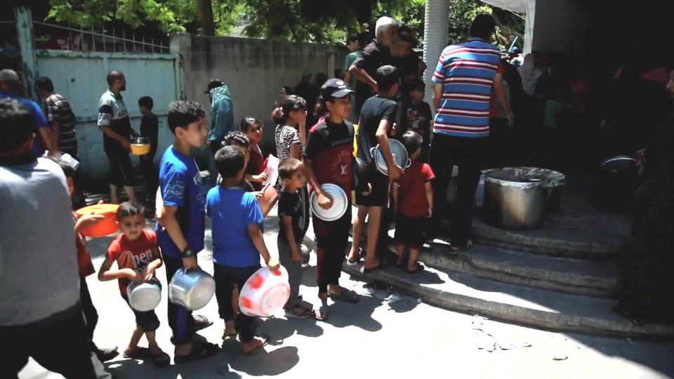 Palestinians in northern Gaza queue  in front of "Tikkeyas" - small food stalls offering free meals