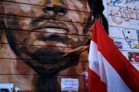 A fan holding an Argentinos Juniors soccer club flag mourns the death of soccer legend Diego Maradona, outside the Diego Armando Maradona stadium, in Buenos Aires