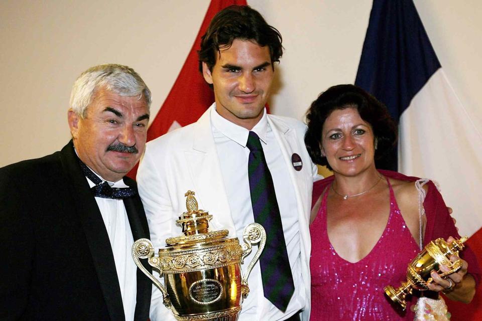 <p>Clive Brunskill/Getty</p> Roger Federer poses with his trophy and parents Lynettee and Robert at the Wimbledon Winners