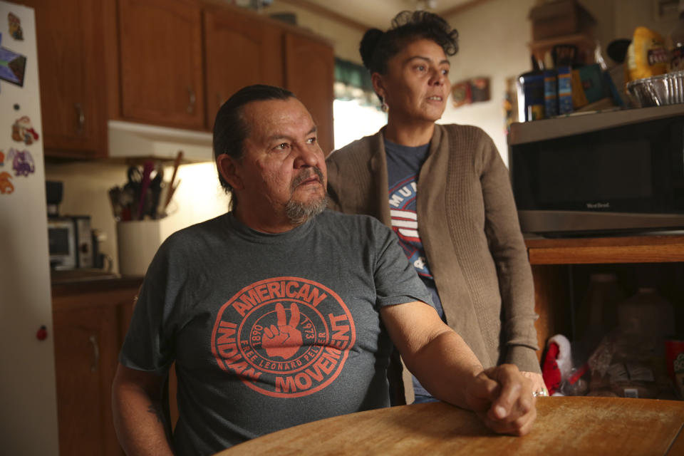 In this Dec. 11, 2019 photo, Henry Red Cloud, and Gloria Red Cloud, look out the window of their home on the Pine Ridge Indian Reservation in South Dakota. They fear what winter storms will do after flooding damaged their home last spring. They ran workshops on solar panel and wind turbine installation, but had to halt the classes when flooding damaged their tools and property. (AP Photo/Stephen Groves)