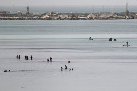 Palestinians dip in the waters of the Mediterranean Sea to cool off during a heat wave as fishermen catch fish off the coast of Gaza City May 23, 2019. REUTERS/Mohammed Salem