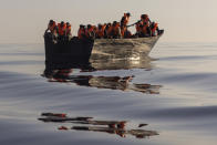 Migrants with life jackets provided by volunteers of the Ocean Viking, a migrant search and rescue ship run by NGOs SOS Mediterranee and the International Federation of Red Cross (IFCR), sit in a wooden boat before being rescued Saturday, Aug. 27, 2022, about 26 nautical miles south of the Italian Lampedusa island in the Mediterranean sea. Eighty seven survivors, including 3 women and 25 minors, were rescued in the operation. (AP Photo/Jeremias Gonzalez)