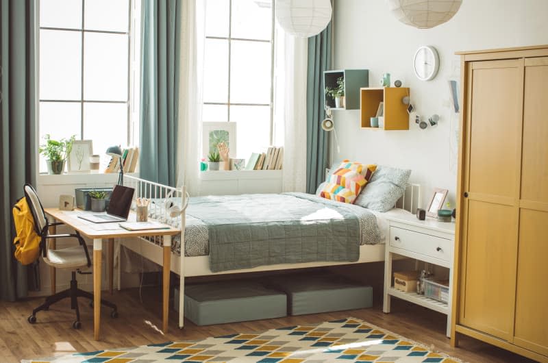 dorm room with bed, big windows, desk, hanging paper lanterns, closet