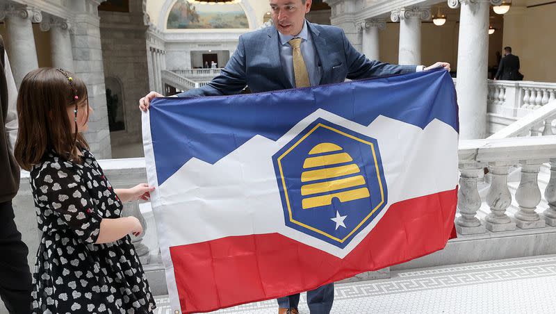 Savanna McCay helps her father, Sen. Daniel McCay, R-Riverton, sponsor of SB31 State Flag Amendments, hold the new Utah state flag at the Capitol in Salt Lake City on March 2, 2023.