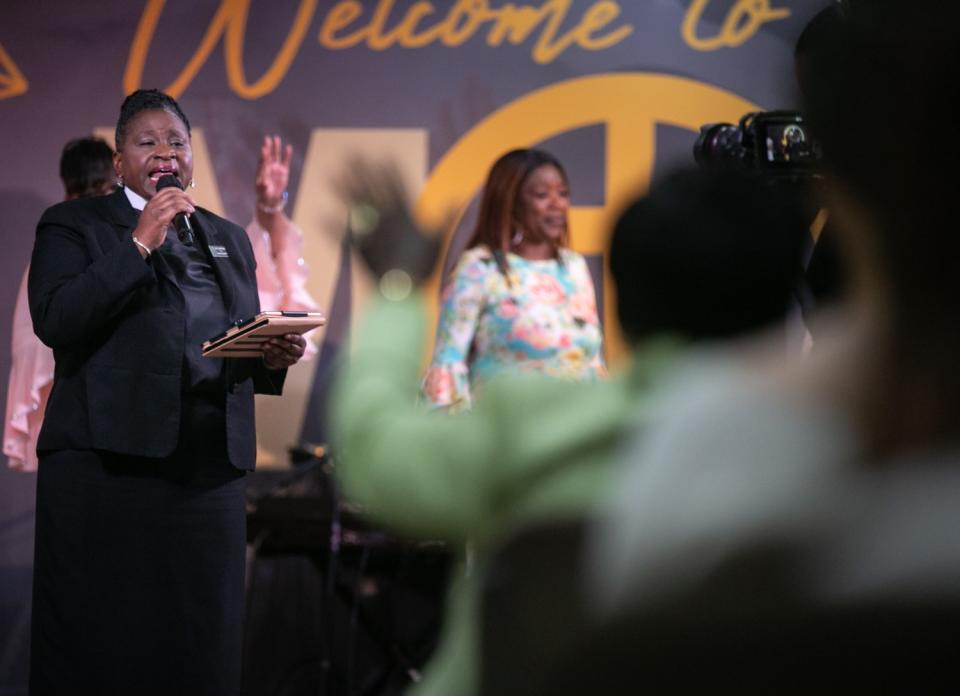 A woman speaks in front of people in seats.