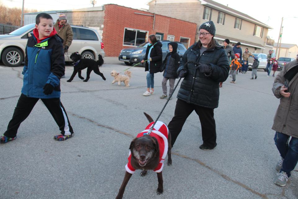 Christopher and Stacy Peterson walk with Cookie during a dog parade before the start of the first annual Van Meter Holiday Tree Lighting Festival on Saturday, Dec. 3, 2022.