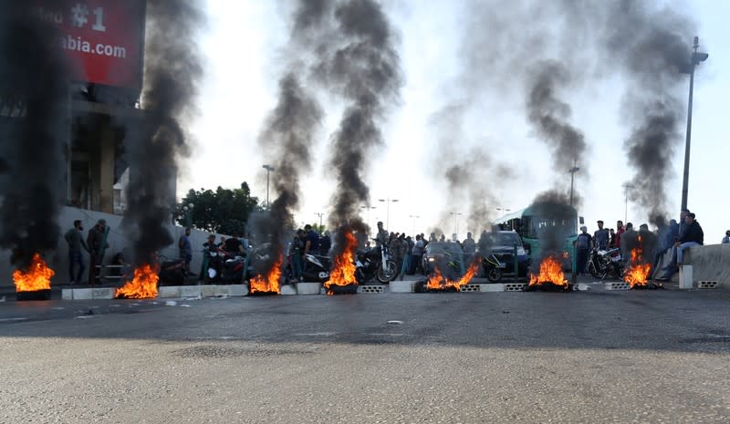 Demonstrators stand near burning tires during ongoing anti-government protests, in Khaldeh