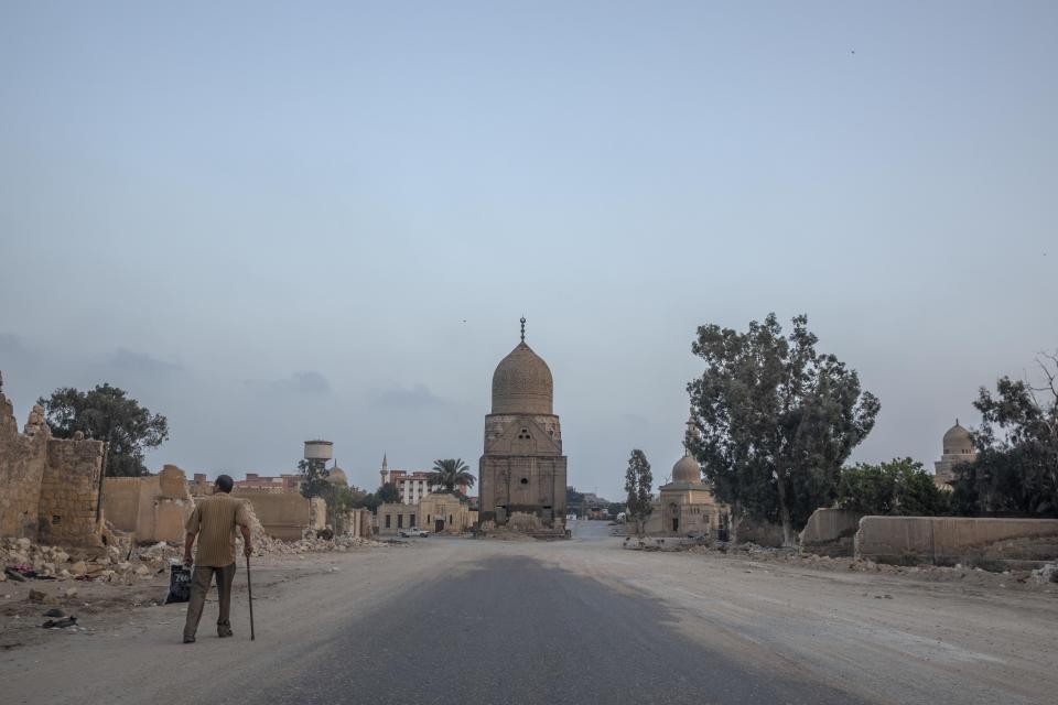 A man looks at graves partially demolished to make way for a new highway through the Northern Cemetery in Cairo, Egypt, Wednesday, July 29, 2020. In the center is the 500-year-old domed tomb of a Mamluk sultan, Qansouh, which was not damaged by the demolitions but will likely be surrounded by the multi-lane expressway. Preservationists have raised alarm over the government's construction of two highways through historic cemeteries, known as the City of Dead, a UNESCO World Heritage Site. (AP Photo/Nariman El-Mofty)