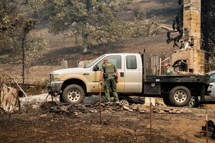 Siskiyou County sheriff's deputies search a scorched residence on Tuesday after the McKinney Fire burned the Klamath National Forest. Their team did not find any fire victims at the property.