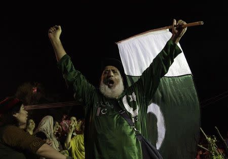 A supporter of Imran Khan, cricketer-turned-opposition politician and chairman of the Pakistan Tehreek-e-Insaf (PTI) political party, gestures holding a national flag while chant slogans during the Freedom March in Islamabad August 18, 2014. REUTERS/Faisal Mhmood