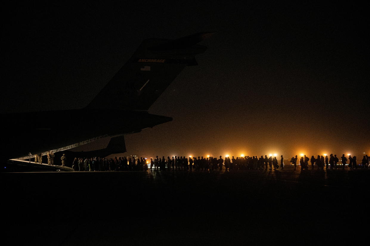 Evacuees from Afghanistan board a military aircraft during an evacuation from Kabul, in this photo taken on August 19, 2021 at undisclosed location and released on August 20, 2021.  (Staff Sgt. Brandon Cribelar/U.S. Marine Corps/Handout via Reuters) 