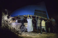 Smugglers lift onto a vehicle a fishing boat intended to be used to transport migrants to the Canary Islands, in a remote desert out of the town of Dakhla in Morocco-administered Western Sahara, Tuesday, Dec. 22, 2020. Beneath a star-packed sky in the Sahara, smugglers and handymen unearth a boat buried in the sand, a made-to-order vessel for carrying migrants from the North African coast to Spain's Canary Islands. (AP Photo/Mosa'ab Elshamy)