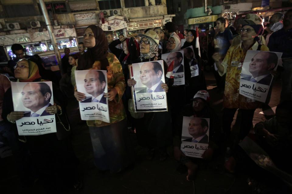 Supporters of Egypt's former army chief Abdel-Fattah el-Sissi hold posters of him with Arabic writing that reads, "Long live Egypt," while watching his first televised interview on a big screen on a street in downtown Cairo, Egypt, Monday, May 5, 2014. El-Sissi gave the first TV interview of his campaign to become Egypt's next president on Monday, saying he decided to run because of the threats facing the nation after his removal of the country's first democratically elected president, Islamist Mohammed Morsi. (AP Photo/Khalil Hamra)