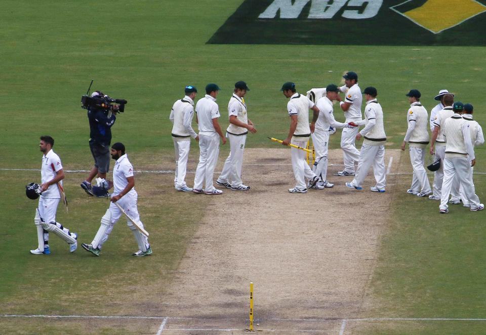 Australia's team celebrate after winning the second Ashes cricket test against England as England's James Anderson (bottom L) and Monty Panesar (bottom 2nd L) walk off the field at the Adelaide Oval December 9, 2013. REUTERS/David Gray (AUSTRALIA - Tags: SPORT CRICKET)