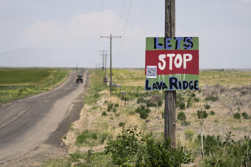 A tractor travels down Hunt Road in front of a "Let's Stop Lava Ridge" sign near the Minidoka National Historic Site, Thursday, July 6, 2023, in Jerome, Idaho. If built to the original proposal, the Lava Ridge wind farm project by Magic Valley Energy, an affiliate of LS Power, would put up to 400 wind turbines in the view shed of the Minidoka National Historic Site. (AP Photo/Lindsey Wasson)