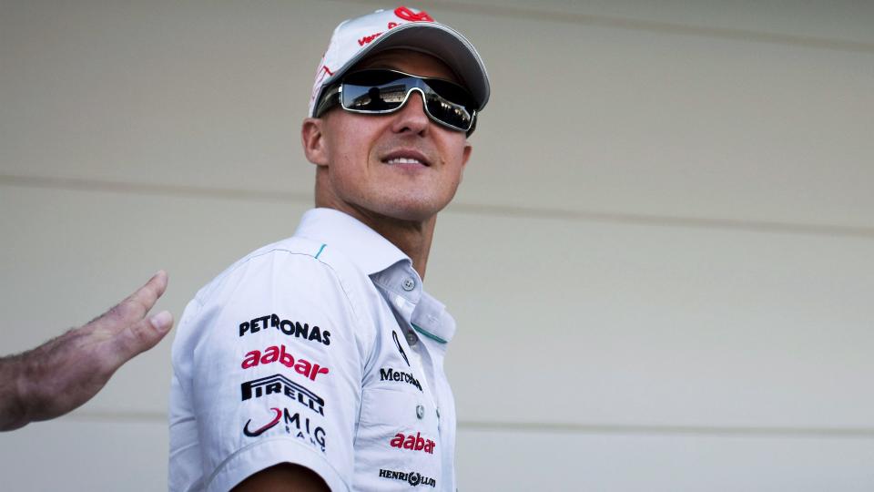 German Mercedes Formula One driver Michael Schumacher wearing dark sunglasses, and smiling in the pit lane as a fan reaches out a hand to touch him before the 2011 Japanese Grand Prix, Suzuka Circuit, Japan, on the 9th October 2011. (Photo by Darren Heath/Getty Images)