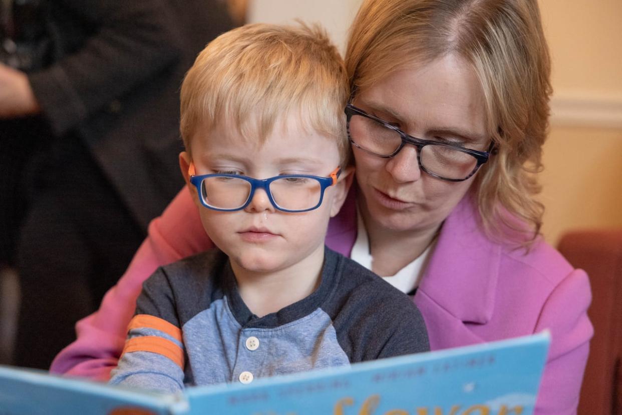 Melanie Waye reads with her son, Xander, during an announcement at Mount Saint Vincent University on Friday. (Robert Short/CBC - image credit)