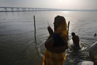 FILE - In this Wednesday, April 1, 2020 file photo, a Hindu devotee performs rituals on Ashtami, eighth day of Navratri festival at Sangam, the confluence of the rivers Ganges and Yamuna in Prayagraj, India. Hindus celebrate Navaratri, or the festival of nine nights, with three days each devoted to the worship of Durga, the goddess of valor, Lakshmi, the goddess of wealth, and Saraswati, the goddess of knowledge. (AP Photo/Rajesh Kumar Singh)