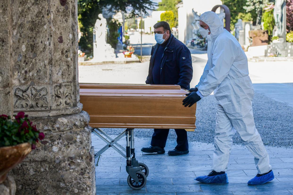 TOPSHOT - An undertaker wearing a face mask and overalls unloads a coffin out of a hearse on March 16, 2020 at the Monumental cemetery of Bergamo, Lombardy, as burials of people who died of the new coronavirus are being conducted at the rythm of one every half hour. (Photo by Piero Cruciatti / AFP) (Photo by PIERO CRUCIATTI/AFP via Getty Images)