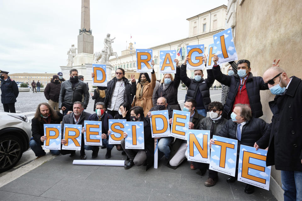 A group of supporters hold placards reading "Draghi President" in front of the Quirinale Presidential palace in Rome Wednesday, Feb. 3, 2021. Former European Central Bank President Mario Draghi arrived for talks with Italian President Sergio Mattarella to discuss a mandate to form a new government. (Mauro Scrobogna/LaPresse via AP)