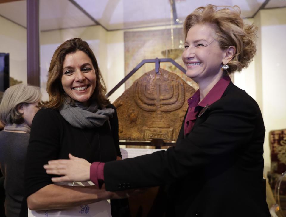 Director of the Vatican Museums, Barbara Jatta, left, and Director of Rome's Jewish Museum Alessandra Di Castro pose for a photo in front of a bas-relief showing a menorah at the end of a press conference in Rome, Monday, Feb. 20, 2017. The Vatican and Rome Jewish community are teaming up for the first- ever joint exhibit by the two institutions' museums. Focus will be the menorah, the candelabra depicted in both Jewish and Catholic art over the centuries. (AP Photo/Alessandra Tarantino)