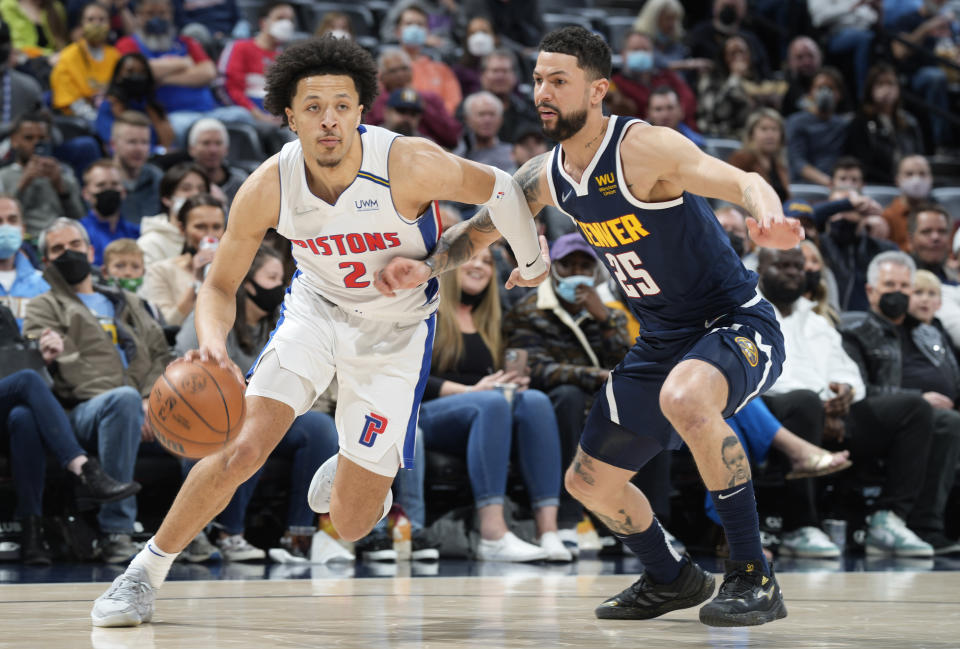 Detroit Pistons guard Cade Cunningham, left, drives past Denver Nuggets guard Austin Rivers in the first half of an NBA basketball game Sunday, Jan. 23, 2022, in Denver. (AP Photo/David Zalubowski)