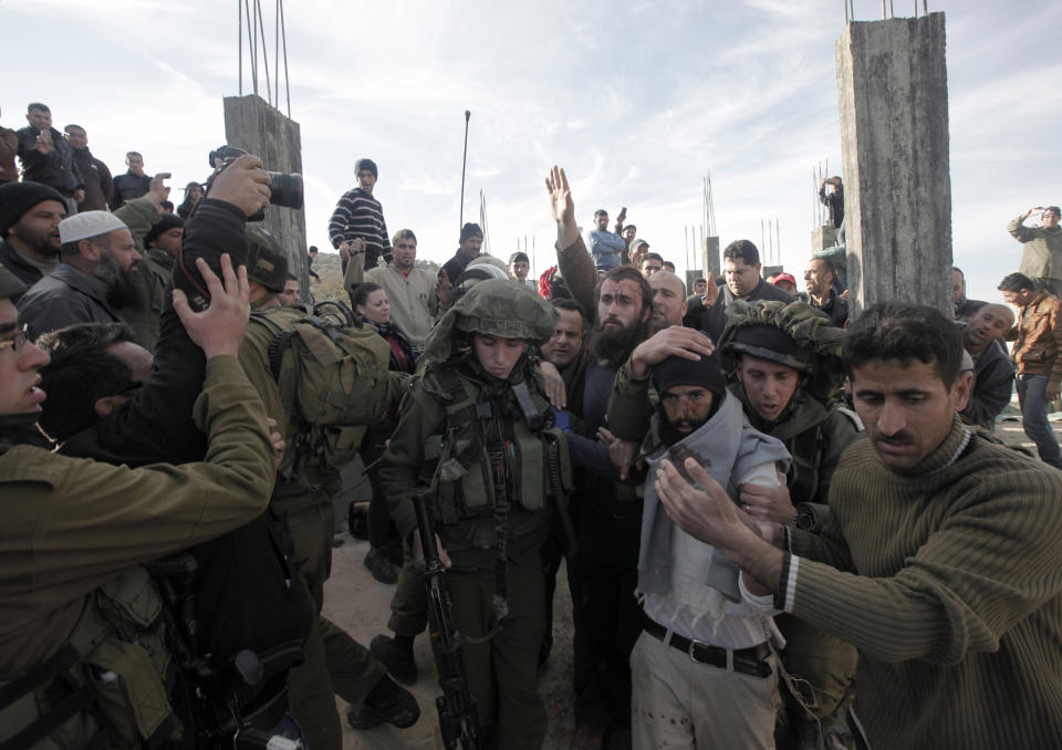 A Palestinian man (R) helps Israeli soldiers to evacuate Israeli settlers after they were detained and beaten by Palestinians from the village of Qusra on Jan. 7, 2014. (JAAFAR ASHTIYEH/AFP/Getty Images)