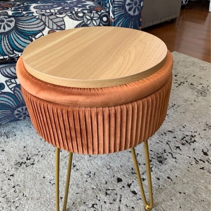 a reviewer photo of the orange ottoman with the lid flipped over showing its wooden surface