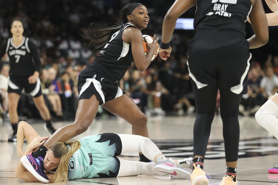 Las Vegas Aces guard Jackie Young (0) attempts to step over New York Liberty guard Sabrina Ionescu (20) during the first half of a WNBA Semifinal basketball game, Sunday, Oct. 6, 2024, in Las Vegas. (AP Photo/Ian Maule)