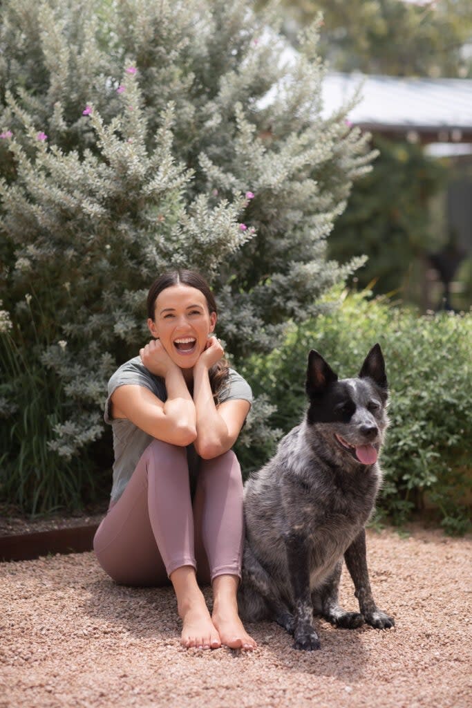 Adriene Mishler sitting outside alongside her dog, Benji