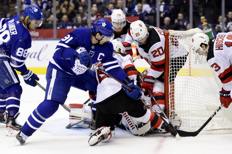 New Jersey Devils goaltender Cory Schneider (35) gets swarmed as Toronto Maple Leafs center John Tavares (91) vies for control of the puck with Devils' Blake Coleman (20) and Nico Hischier (13) while Maple Leafs right wing William Nylander (88) and Devils' Damon Severson (28) watch during the second period of an NHL hockey game Tuesday, Jan. 14, 2020, in Toronto. (Frank Gunn/The Canadian Press via AP)