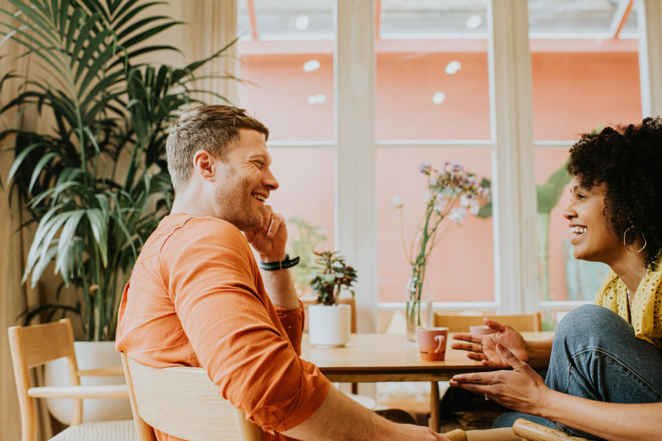 A man and a woman are face-to-face in a stylish environment. Their body language suggests they are very comfortable with each other, and enjoying time together as they have a lighthearted, emphatic and animated discussion. They both smile. Space for copy.