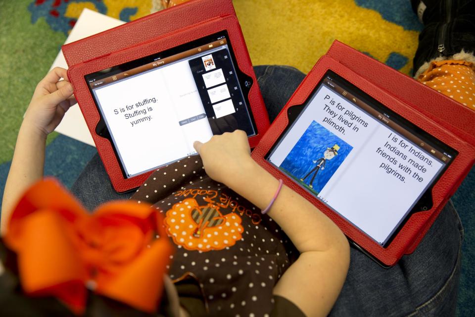 This photo taken Nov. 25, 2013 shows Isabelle Fontana, 7, working on two iPads for an e-book about Thanksgiving in her second grade classroom at Jamestown Elementary School in Arlington, Va. Isabelle was working on the text as a classmate made drawings to be photographed and inserted in the e-book. Needed to keep a school building running these days: Water, electricity _ and broadband. Interactive digital learning on laptops and tablets is, in many cases, replacing traditional textbooks. Students are taking computer-based tests instead of fill-in-the bubble exams. Teachers are accessing far-off resources for lessons. (AP Photo/Jacquelyn Martin)