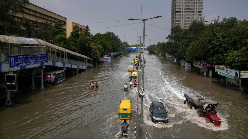 Commuters drive through a street inundated with floodwaters from the swollen river Yamuna, in New Delhi, India, Friday, July 14, 2023. - Manish Swarup/AP