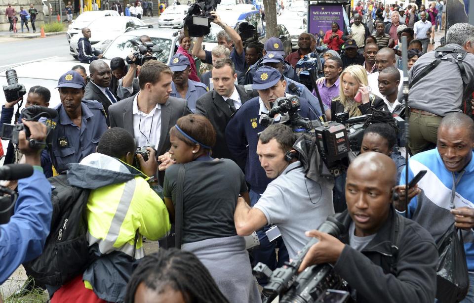Oscar Pistorius, back center, is mobbed by media as he is escorted by police outside court during a recess on the third day of his trial at the high court in Pretoria, South Africa, Wednesday, March 5, 2014, Pistorius is charged with murder for the shooting death of his girlfriend, Reeva Steenkamp, on Valentines Day in 2013. (AP Photo/Antoine de Ras) SOUTH AFRICA OUT