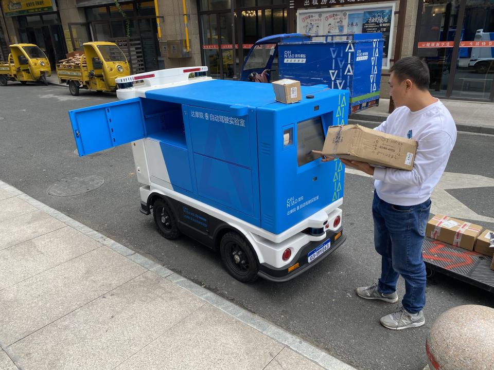 Cainiao engineer Long Fei loads packages onto the firm’s Xiao G automated delivery vehicle in Hangzhou, China on Oct. 19, 2020.<span class="copyright">Charlie Campbell</span>