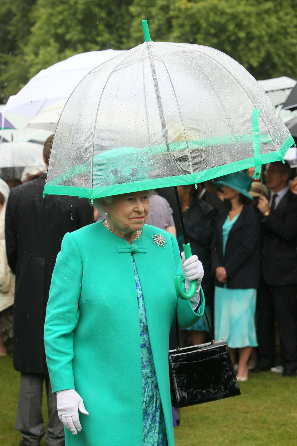 Britain's Queen Elizabeth II shelters from the rain under an umbrella as she hosts a garden party at Buckingham Palace, in central London.   (Photo by Dominic Lipinski/PA Images via Getty Images)