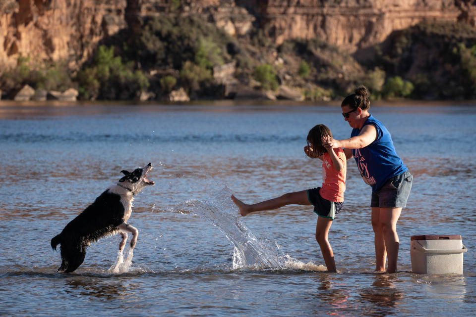 Leah Forni (right) and her daughter, Emily Forni (center, both from Ohio) play with their dog, Mylo, May 24, 2022, in the Colorado River at Lees Ferry, Arizona.